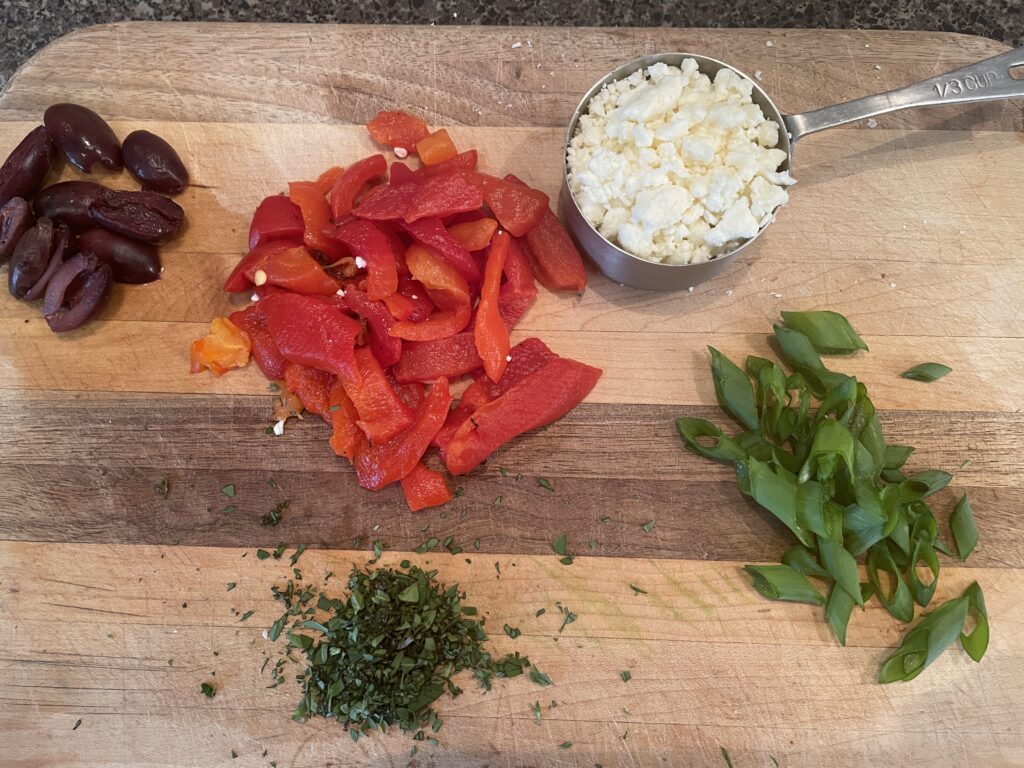 Pizza ingredients: feta cheese, green onions, red peppers, oregano, kalamata olives