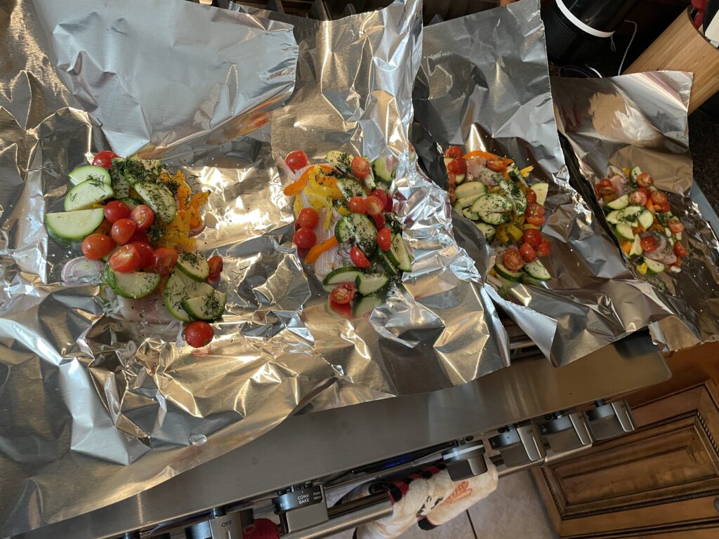 Four mahi mahi, vegetable and herb portions ready to fold up