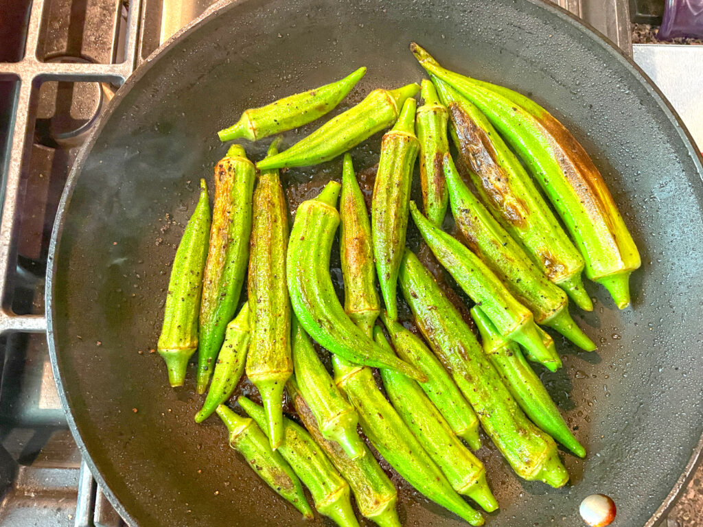 Okra in the pan with olive oil, salt, and black pepper.