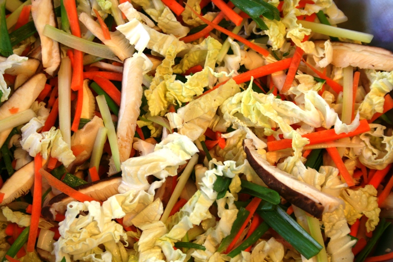 The marinated filler vegetables, rice paper sheets, and cool water bath